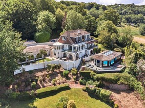 A large, multi-story house with a spacious patio area, surrounded by lush greenery and a well-maintained garden. - Ocean-view Manor With Jacuzzi (Torquay)
