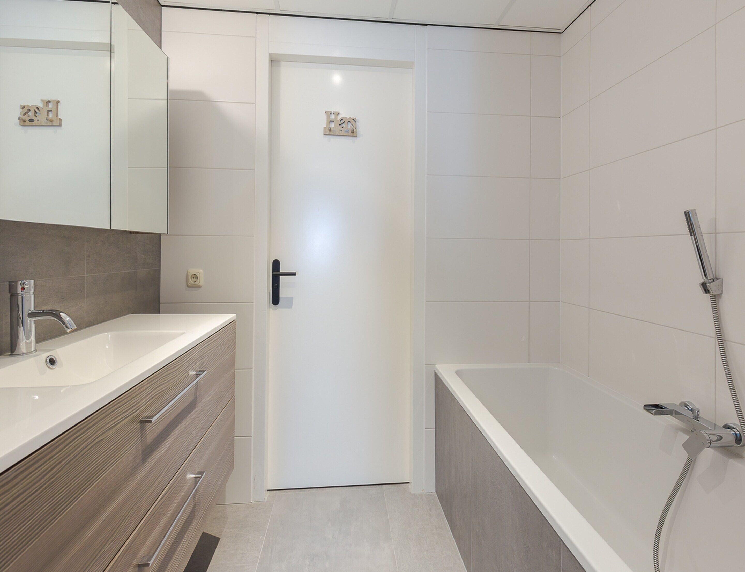 Een moderne badkamer met een witte wastafel, spiegel en douche.