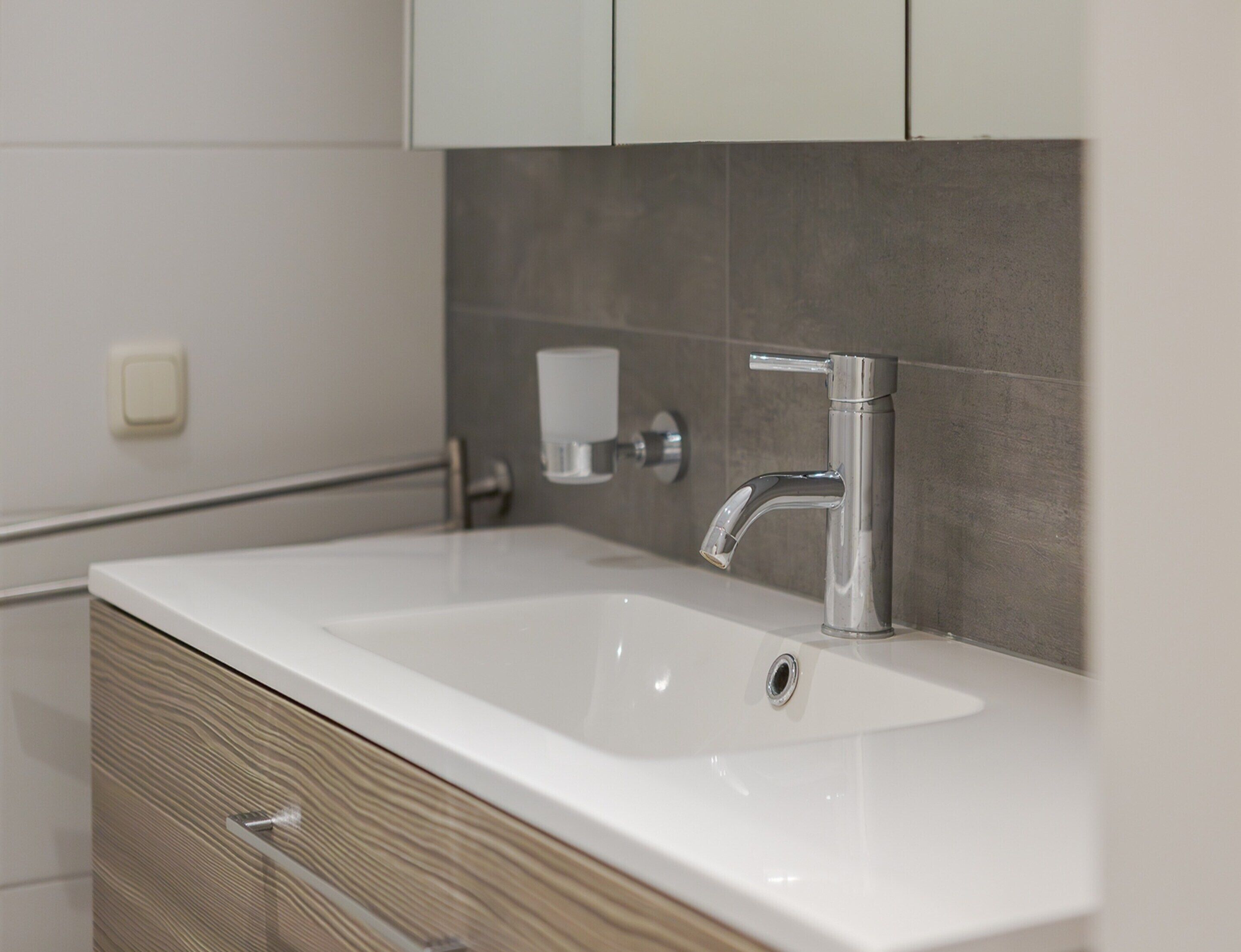 Une salle de bain moderne avec un lavabo blanc, un robinet chromé et un meuble en bois.