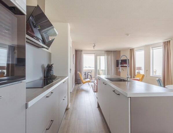 A compact kitchen with a coffee maker, a sink, and a dining area with a chair and table.