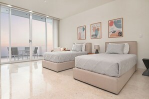 A modern hotel room with two beds, a balcony, and abstract wall art. - Breathtaking Oceanfront Luxury Penthouse! (San Miguel de Cozumel)