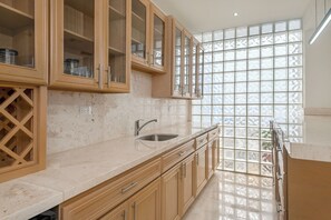 Eine Küche mit Holzausstattung, einem Edelstahlspülbecken und einem großen Fenster mit Gitterstruktur.