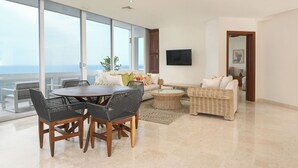 Un ampio soggiorno con balcone vista mare, arredato con un tavolo da pranzo, sedie, divani e una TV.