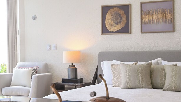 Un soggiorno con un divano, una lampada e elementi decorativi alle pareti.