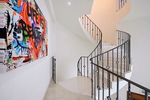 Eine Treppe mit schwarzer Metallreling und weißer Wand.