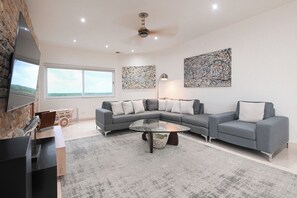 A modern living room with a sectional sofa, a glass coffee table, and artwork on the walls. - Breathtaking Oceanfront Luxury Penthouse! (San Miguel de Cozumel)