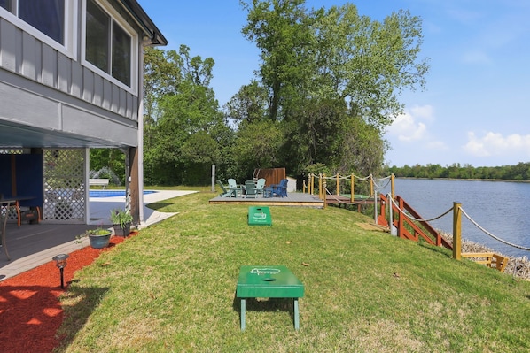 A lakeside property with a deck, outdoor seating, and a small green table.