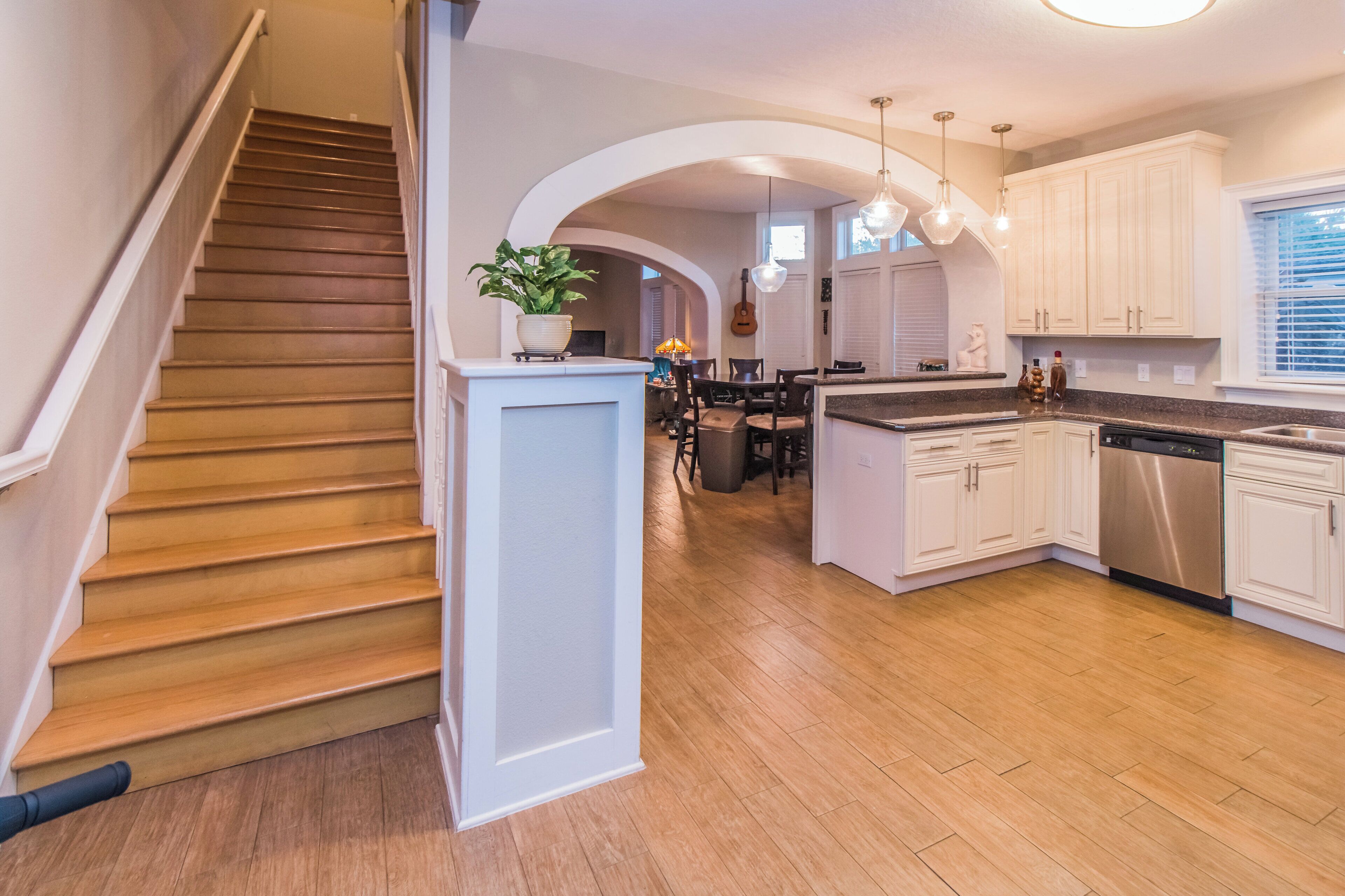 A modern kitchen with wooden flooring, white cabinetry, and a central island.
