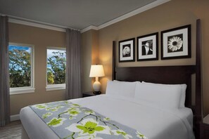 Ein Hotelzimmer mit einem Bett, einem Nachttisch mit Lampe und drei gerahmten Bildern an der Wand.