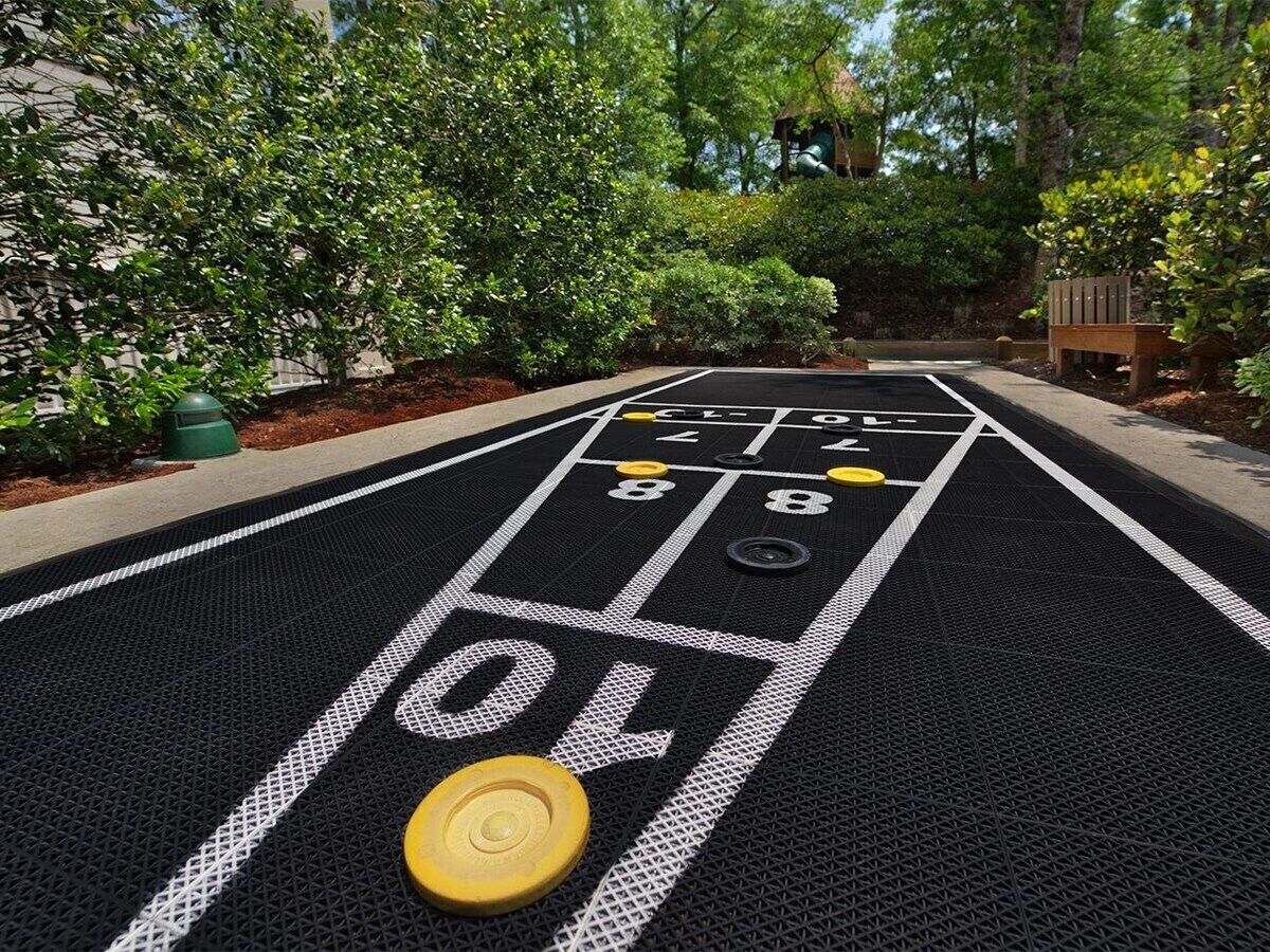 A shuffleboard table with numbered scoring areas and a puck in the foreground.