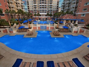 A large indoor swimming pool with multiple lounge chairs and umbrellas, surrounded by a high-rise building with balconies. - 2 Bedroom Villa at Marriott OceanWatch Resort (Myrtle Beach)