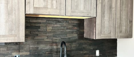 A kitchen with wooden cabinets, a black faucet, and a stone backsplash.
