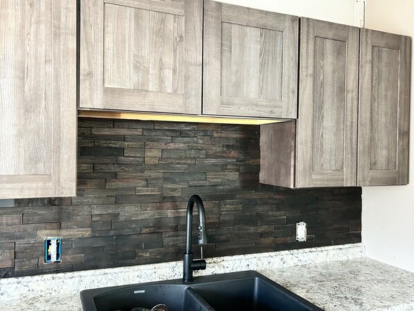 A kitchen with wooden cabinets, a black faucet, and a stone backsplash.