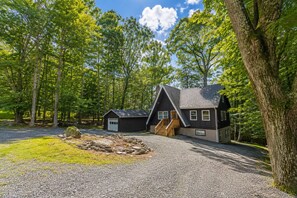 A cabin with a gravel driveway, surrounded by trees. - Spacious 6BR Pocono Retreat / 5 Min to Lake Wallenpaupack./ Sleeps 12 / 3 pools (Lake Ariel)