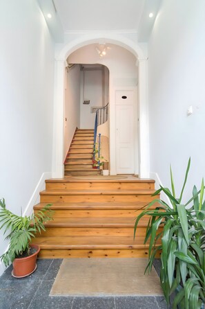 Eine Treppe mit Holzstufen führt zu einer Zwischenebene, die von Kübelpflanzen gesäumt wird.