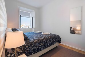 A bedroom with a bed, a window, a bedside lamp, and a wall-mounted mirror. - 'Graça' Apartment with Private Terrace (Lisbon)