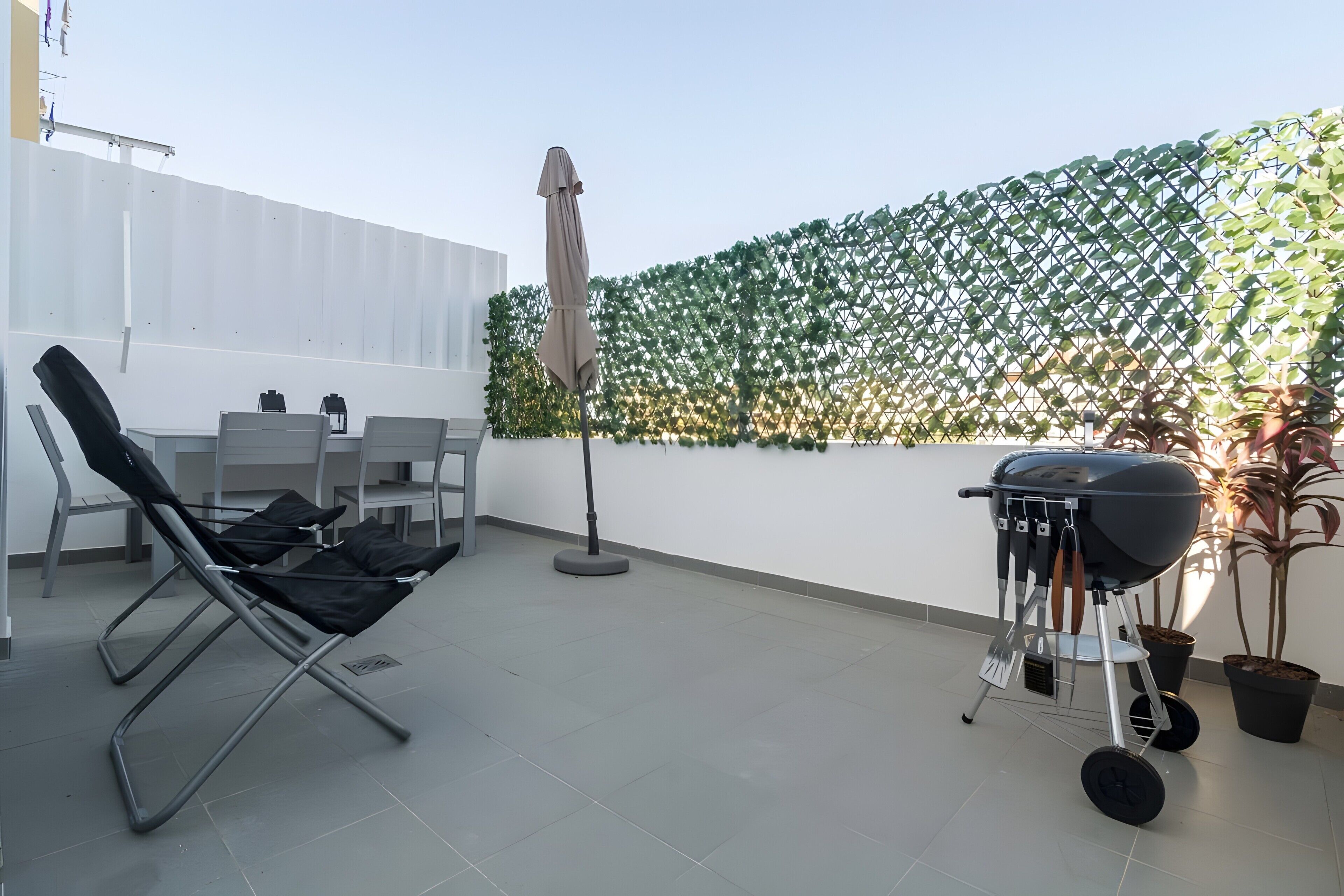 Una terraza en la azotea con zona de estar, una parrilla y una barandilla decorativa.
