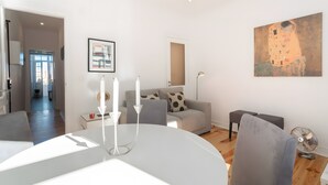 Uma sala de estar moderna com área de jantar, sofá, mesa com velas e um quadro na parede.