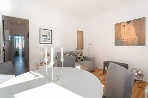 Ein modernes Wohnzimmer mit Essbereich, einer Couch, einem Tisch mit Kerzen und einem Gemälde an der Wand.