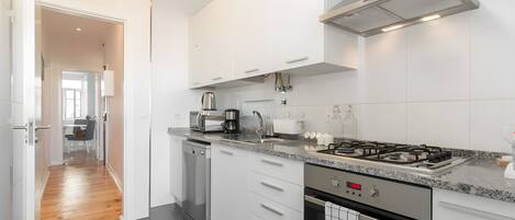 A modern kitchen with white cabinetry, a stainless steel range hood, a built-in dishwasher, and a gas stove.