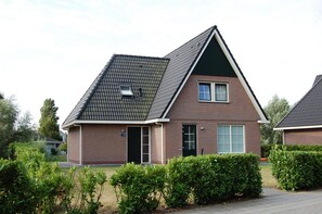 A modern two-story house with a sloped roof, a front door, and a small window. - Family Beach Villa With Outdoor Spa (Makkum)