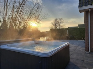 A hot tub outdoors with a sunset in the background. - Family Beach Villa With Outdoor Spa (Makkum)
