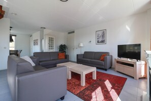 A modern living room with two sofas, a coffee table, a TV, and a red rug. - Family Beach Villa With Outdoor Spa (Makkum)