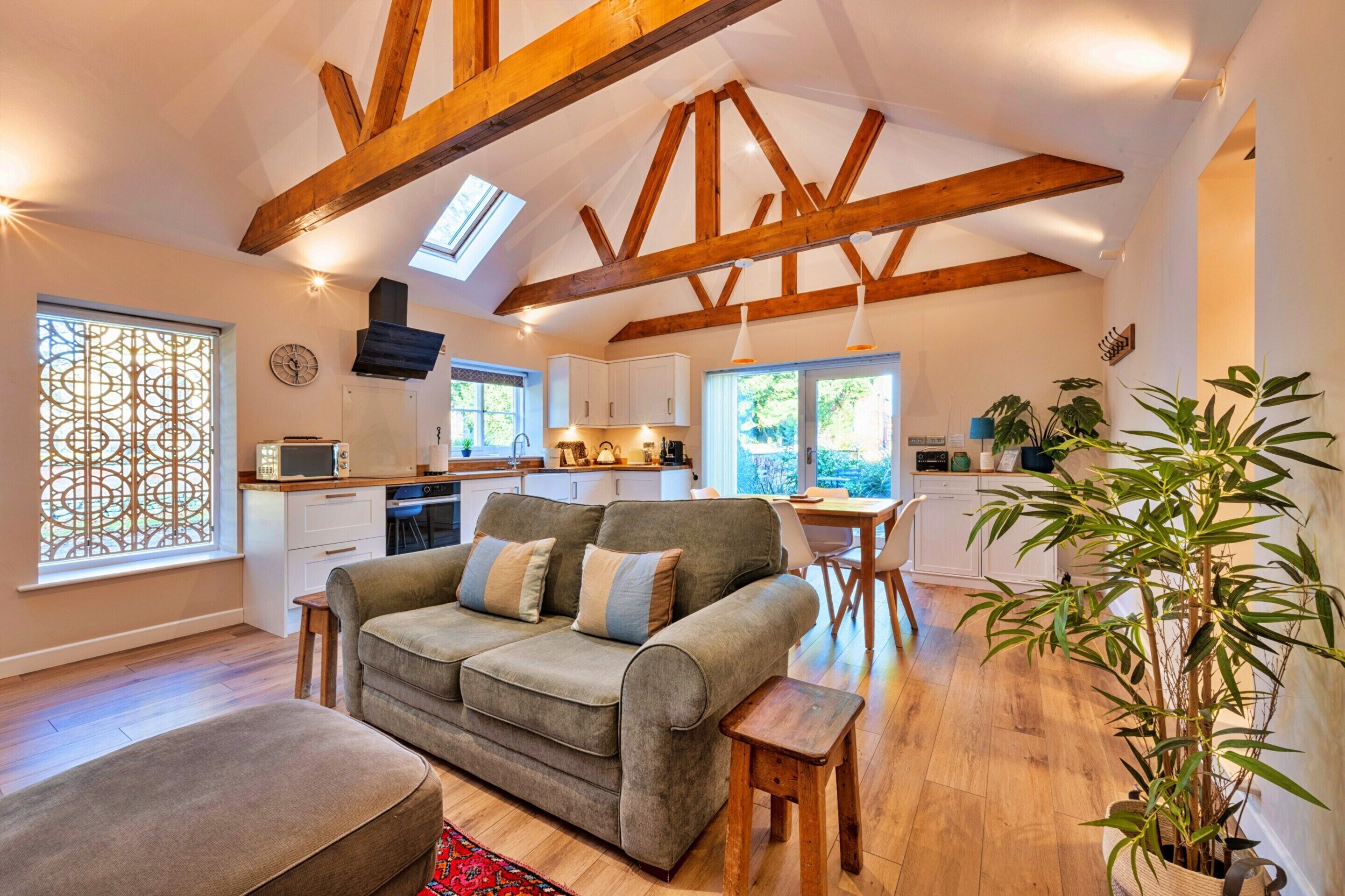 A spacious living room with a sofa, ottoman, and a dining area with a table and chairs.