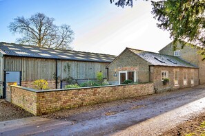 A brick building with a metal roof, a wooden fence, and a gravel driveway. - Romantic Retreat in Lincolnshire (Sleaford)