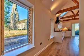 A modern kitchen with wooden beams, a large window, and a view of a church. - Romantic Retreat in Lincolnshire (Sleaford)