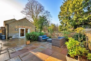 A brick building with a patio area featuring outdoor furniture and a variety of plants. - Romantic Retreat in Lincolnshire (Sleaford)