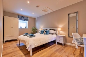 A bedroom with a bed, bedside tables, a chair, a wardrobe, a window with curtains, and a mirror. - Romantic Retreat in Lincolnshire (Sleaford)