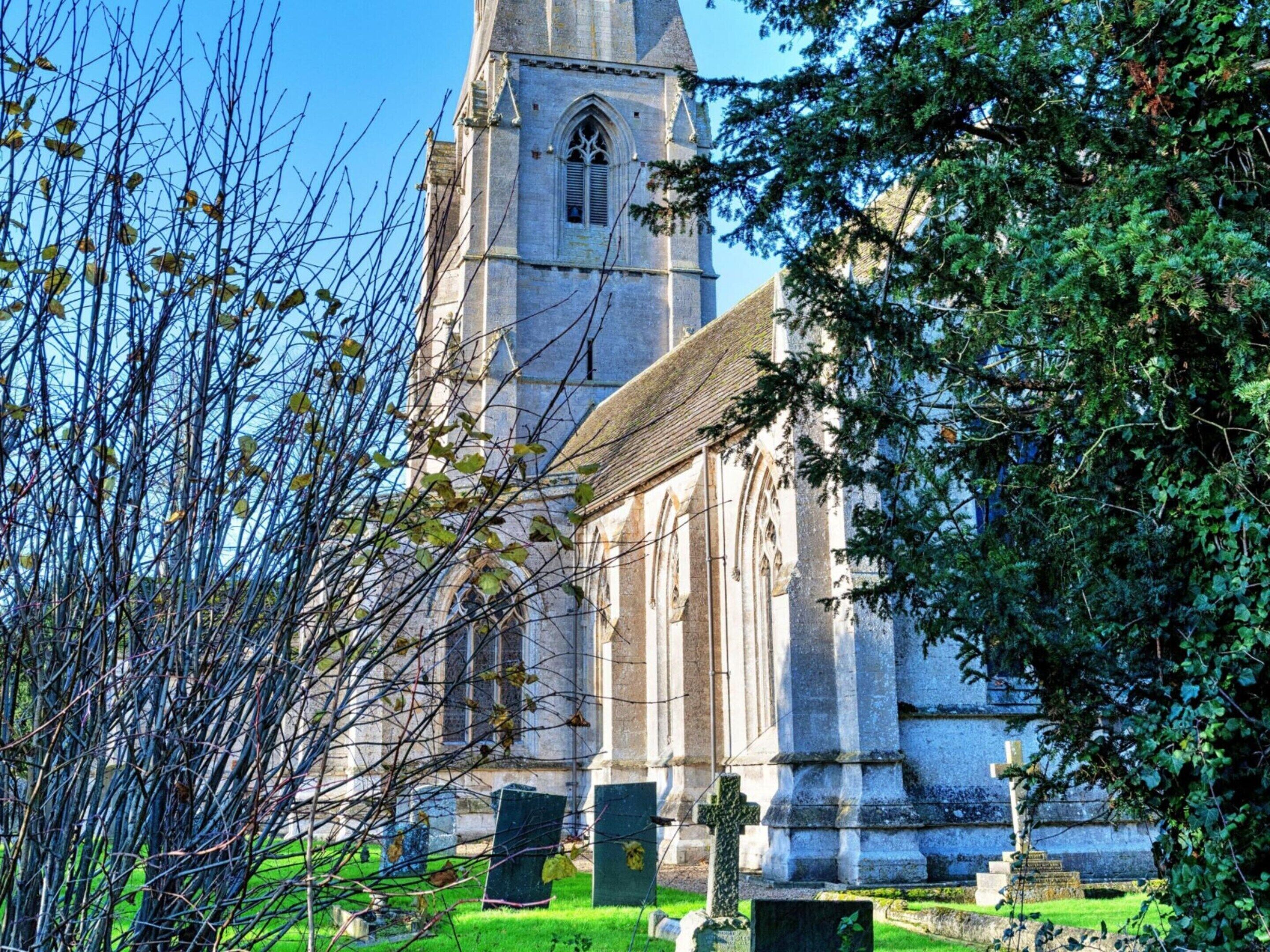 Eine Kirche mit hohem Turm und einem Friedhof davor.