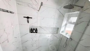 Um banheiro com chuveiro, um armário com artigos de higiene pessoal e uma janela.