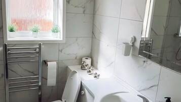 Een bad/douchecombinatie, een diep bad, handdoeken