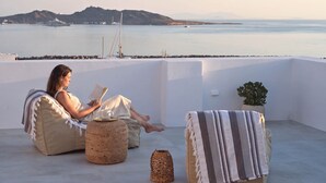 A person relaxing on a balcony with a view of the sea and boats. - Parian Pearl · Naousa 180° SeaView · Walk to Beach (Nauosa)