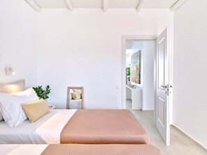 A bedroom with a bed, bedside table, and a small seating area. - Parian Pearl · Naousa 180° SeaView · Walk to Beach (Nauosa)