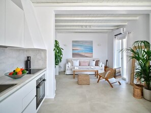 A modern kitchen with a dining area, a sofa, and a guitar. - Parian Pearl · Naousa 180° SeaView · Walk to Beach (Nauosa)