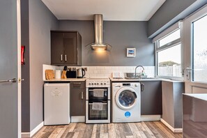 Eine kompakte Küche mit Einbauofen, Waschmaschine und kleinem Kühlschrank.