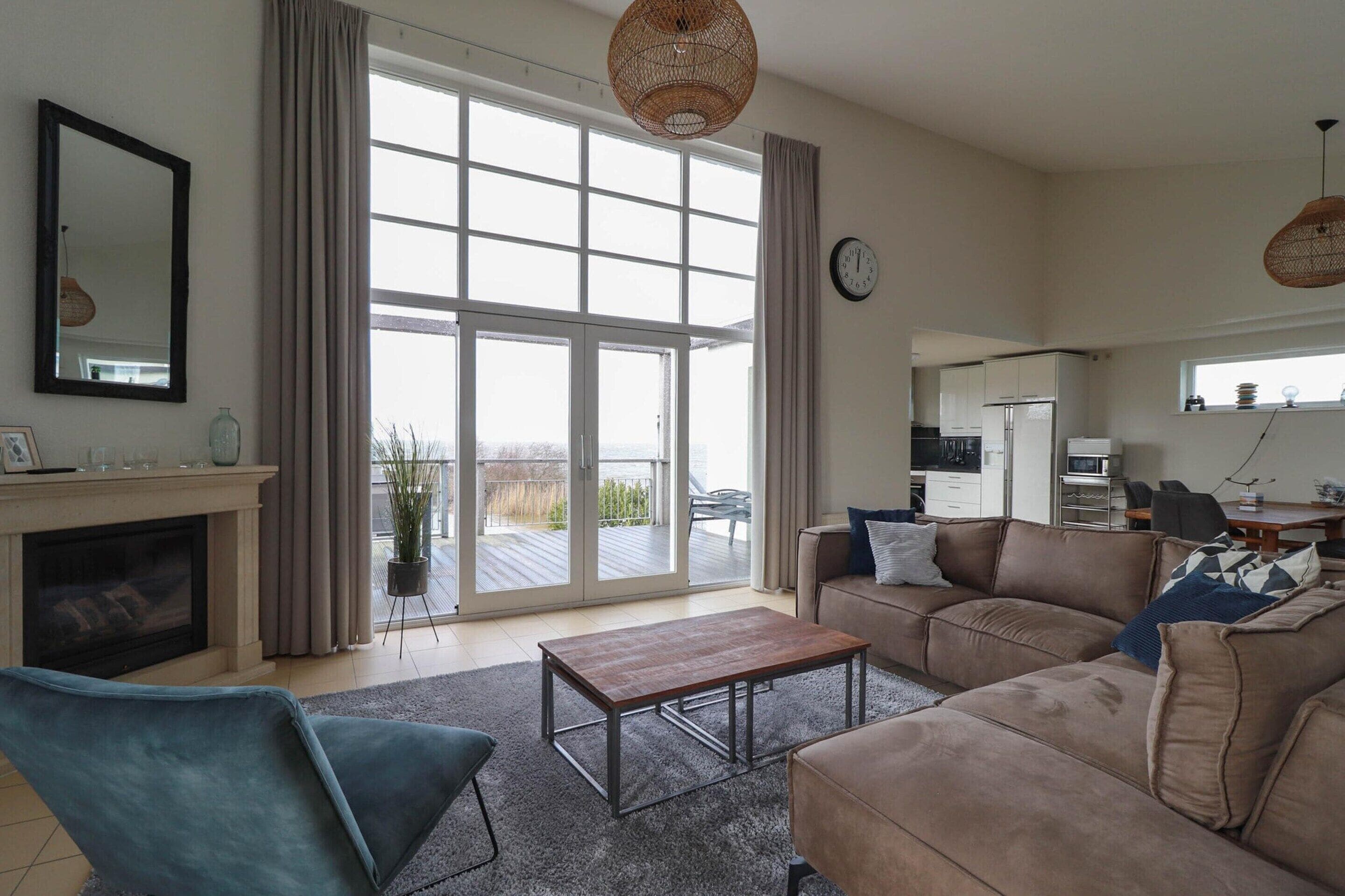 A spacious living room with a fireplace, a sofa set, a coffee table, and a large sliding glass door leading to a balcony.