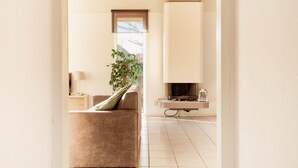 A modern living room with a sofa, a plant, and a fireplace. - Detached Waterfront Villa With Garden (Makkum)