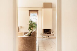 Ein modernes Wohnzimmer mit einer Couch, einer Pflanze und einem Kamin.
