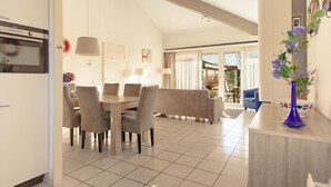 A modern kitchen with a dining area, a blue sofa, and a vase with flowers. - Detached Waterfront Villa With Garden (Makkum)