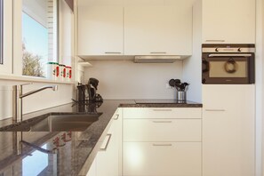 Eine moderne Küche mit weißen Schränken, einer Edelstahl-Spüle und einem eingebauten Backofen.