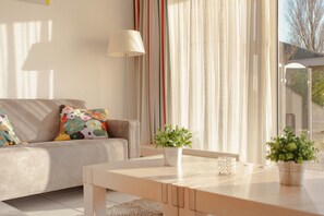 Ein modernes Wohnzimmer mit einer Couch, einem Couchtisch und einer Topfpflanze.