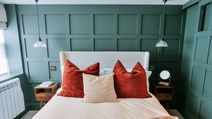 A bedroom with a bed, two nightstands, a radiator, and a window. - Weald Base for Four Guests (Tenterden)