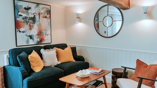 A living room with a dark blue sofa, a round mirror, and a coffee table. - Weald Base for Four Guests (Tenterden)