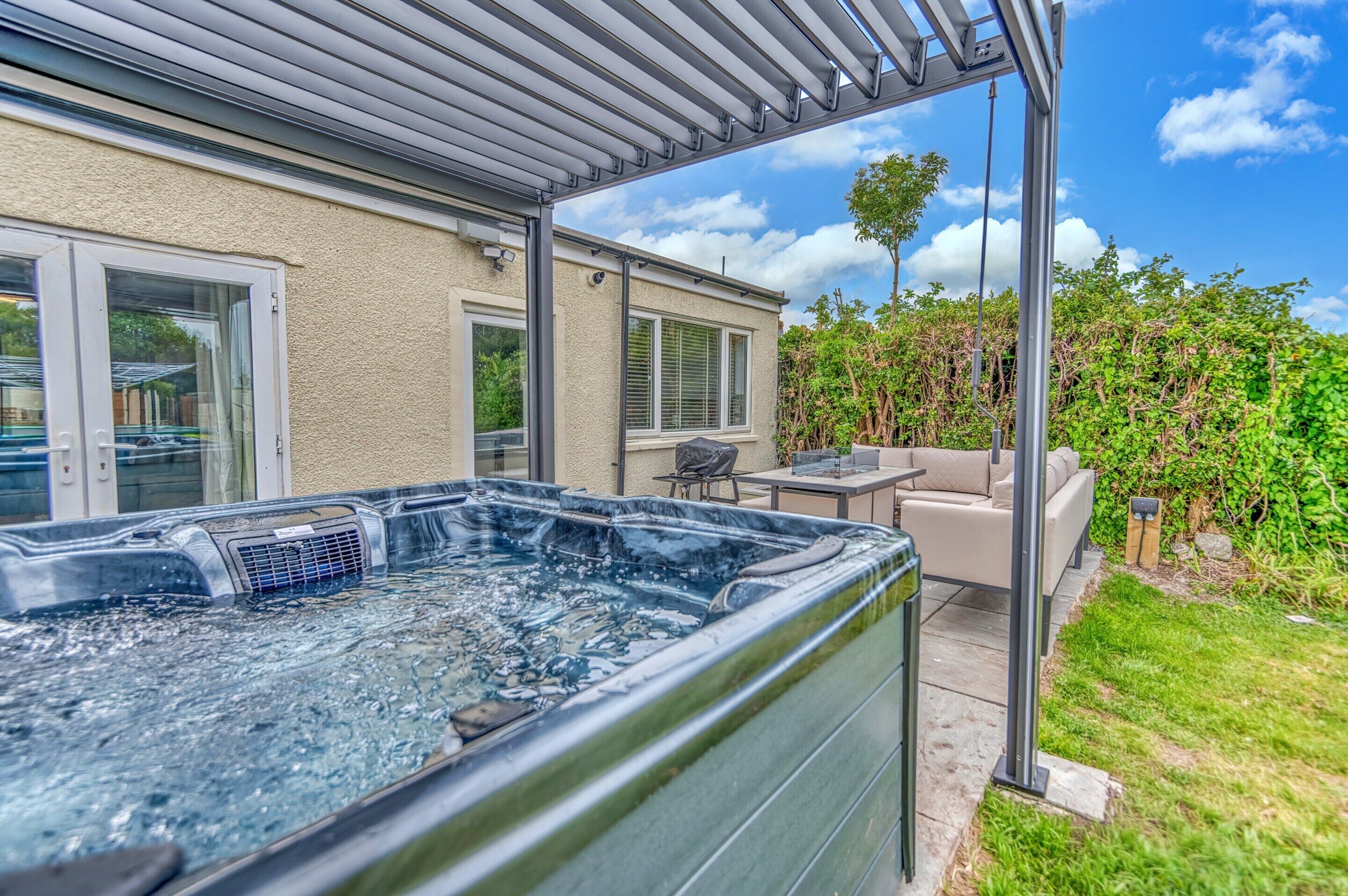 A hot tub in a covered outdoor area with a patio and seating.