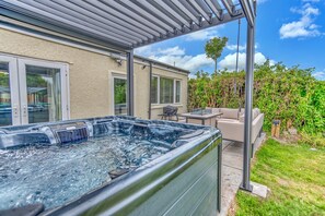 A hot tub in a covered outdoor area with a patio and seating. - Romantic Devon Cottage for 2 (Pembroke Dock)