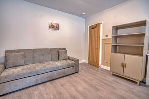 A room with a grey sofa, a wooden wardrobe, and a door. - Romantic Devon Cottage for 2 (Pembroke Dock)